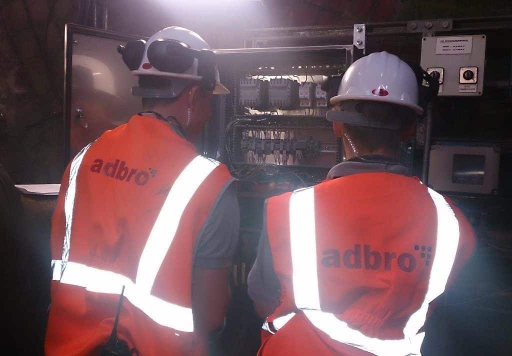 Two adbro controls engineers looking into control panel